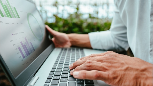 A man using a laptop with its screen displaying a circle chart and bar graphs
