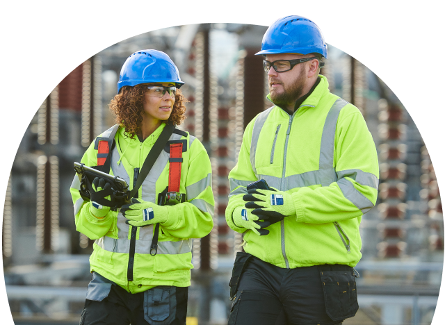 Two safety-vested engineers discussing work outdoors